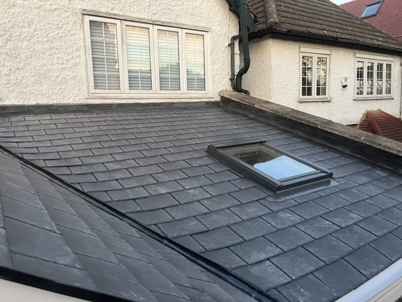 The finished slate-grey roof close up, showing the courses and the new roof window