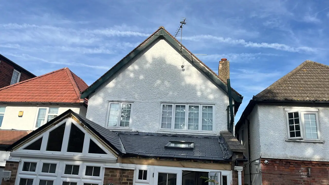 The same elevation with a solid slate-grey tiled conservatory roof and a roof window