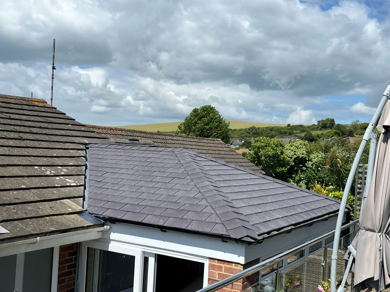 The same roof re-covered in new slate-grey tiles with a clean hip and new eaves